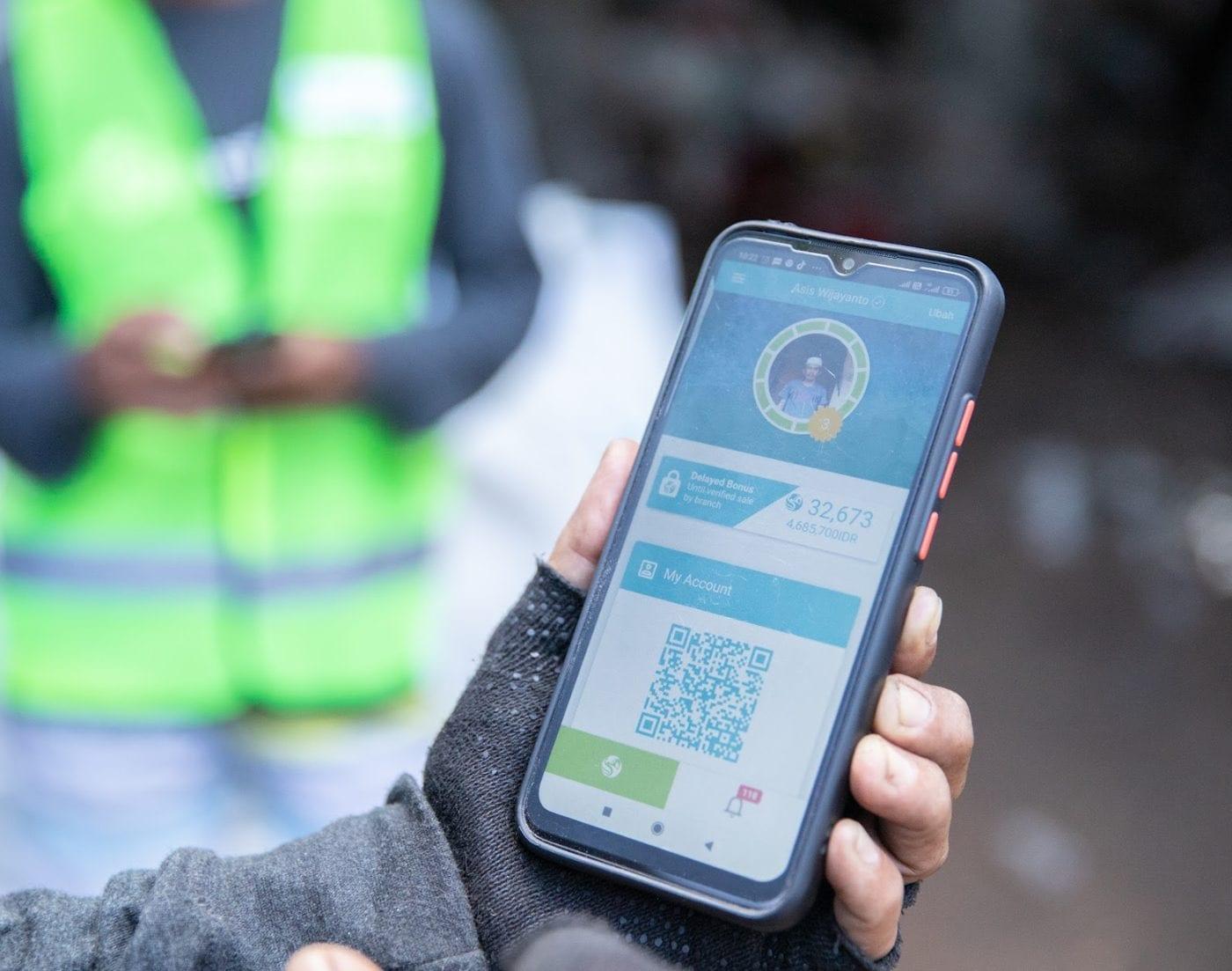 A collector's phone showing the Plastic Bank app and a QR code