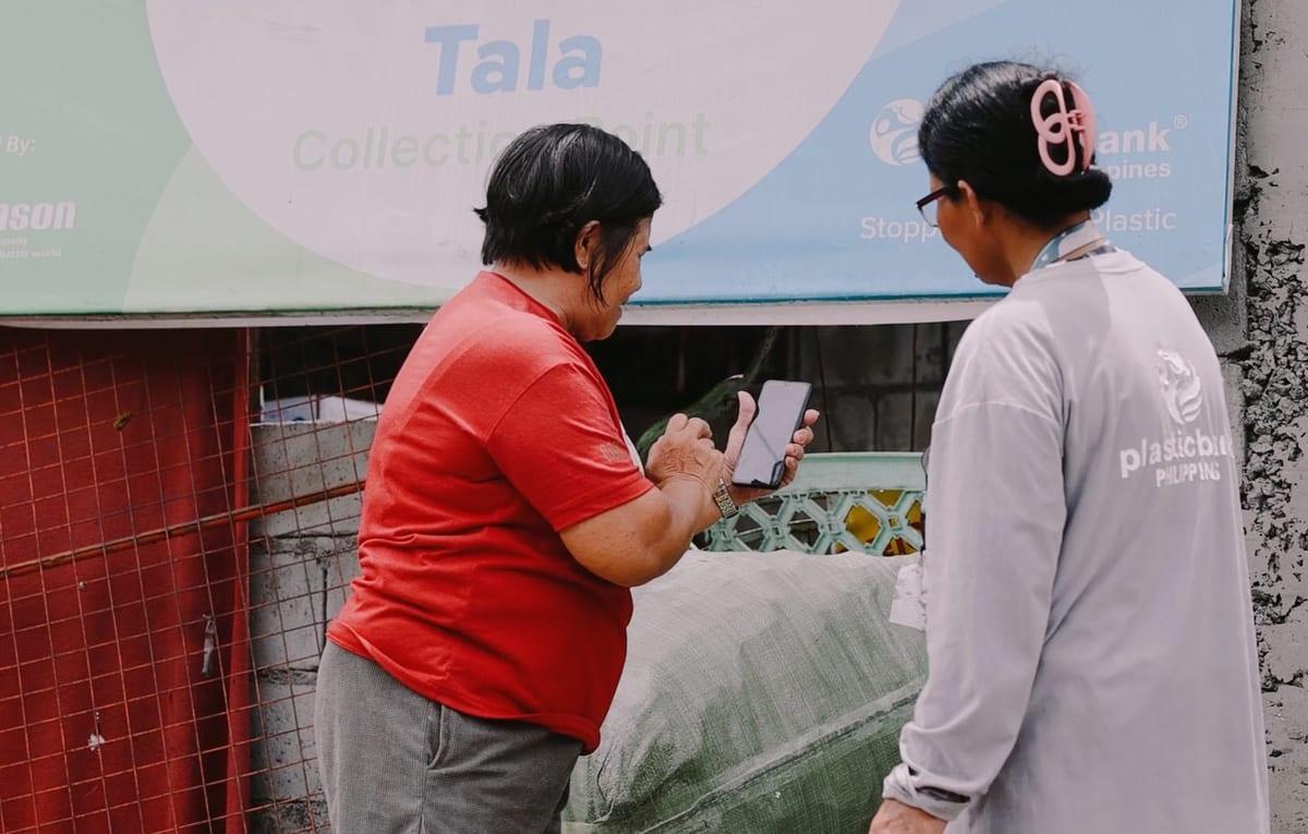 Two Plastic Bank members checking a collection on a phone in the Philippines