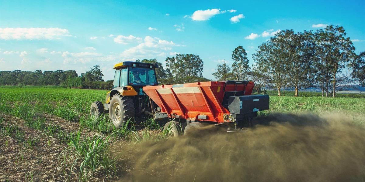 A tractor spreading crushed rock across a field