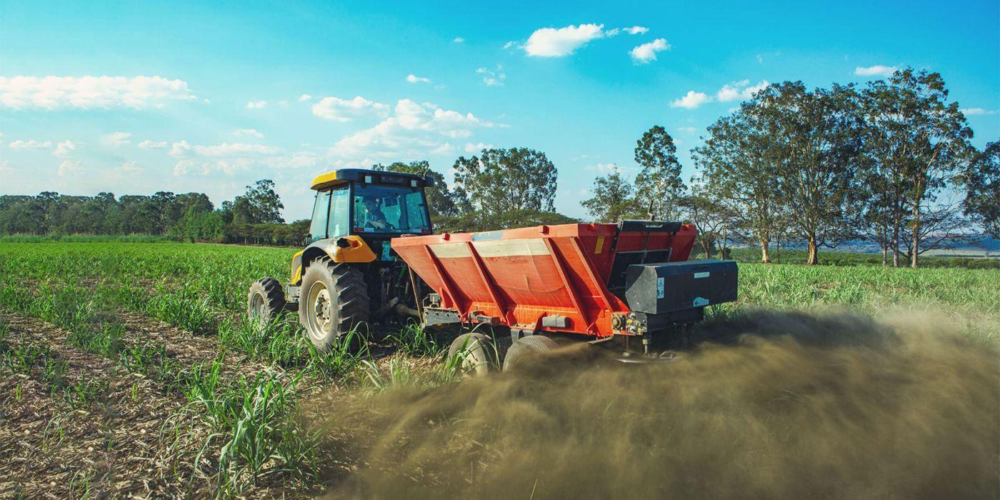 A tractor spreading crushed rock across a field to capture carbon