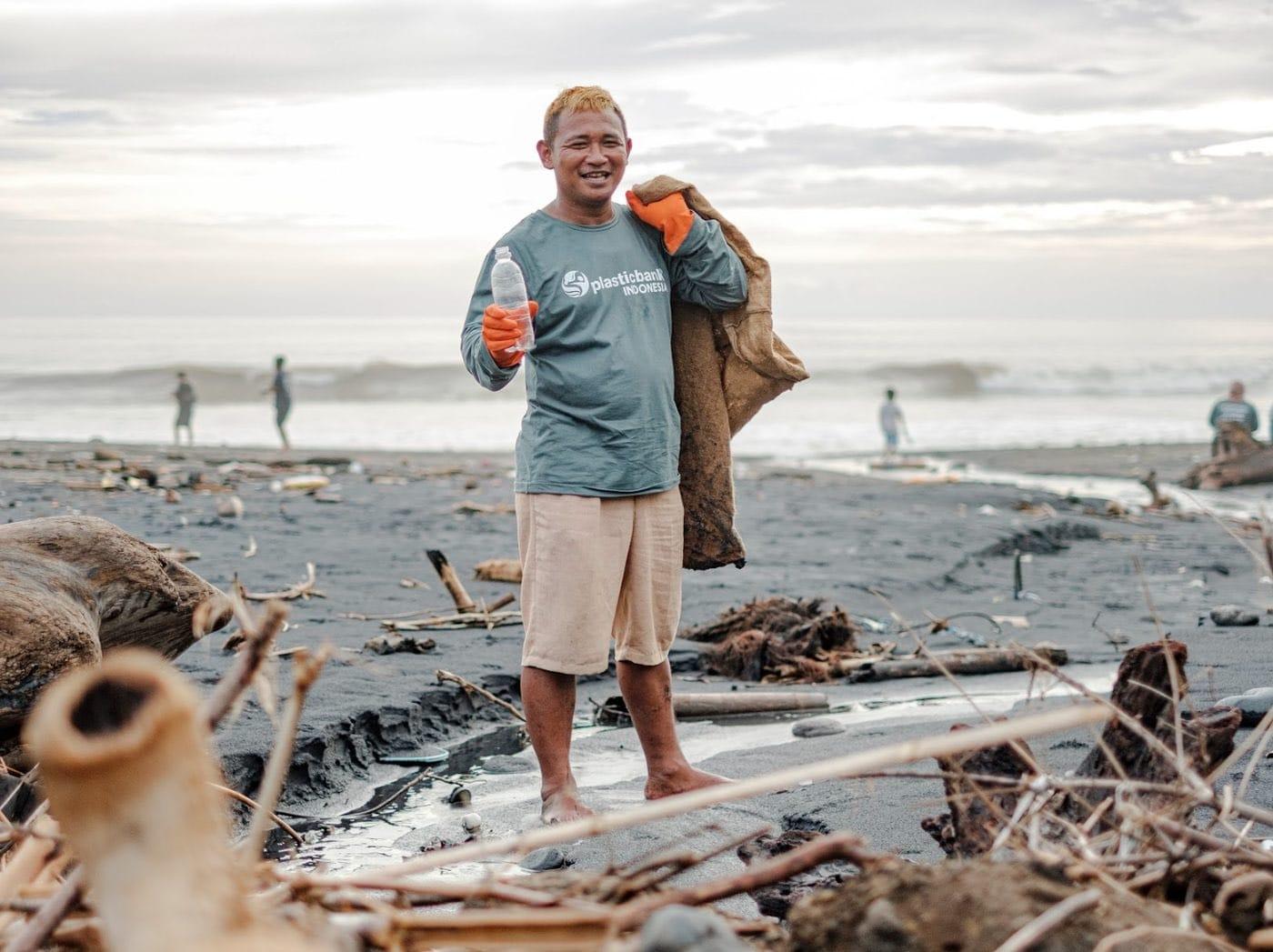 A Plastic Bank collector on a beach in Indonesia holding a plastic bottle