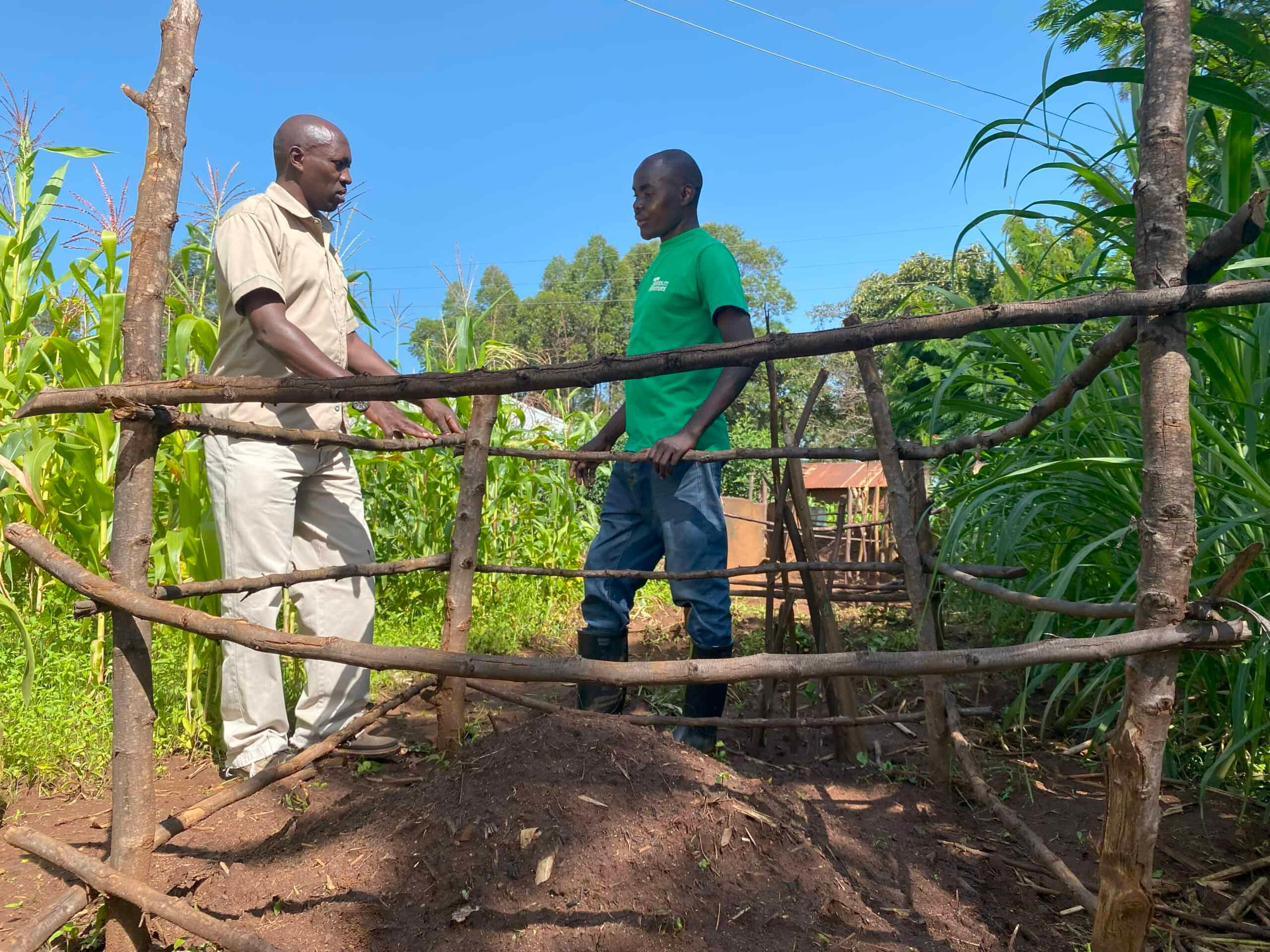 TREES Seed Bank Manager Robert Ochieng (left) visits with David at his compost pile to check in and see how his Forest Garden is progressing.
